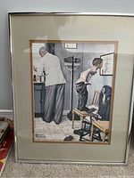 Norman Rockwell framed print showing a doctor with a child in a clinical setting, framed in silver metal with double mat.