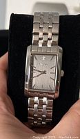 Bulova women's wristwatch, silver-tone with rectangular face and metal linked band, displayed in black velvet holder.
