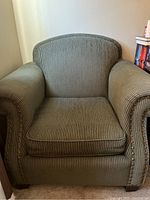 Front view of green corduroy upholstered chair with cushioned seat and backrest.