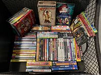 Wide view showing multiple DVD titles arranged in stacks and rows on a black chair.