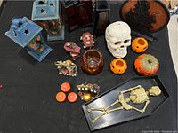 Full lot view showing various Halloween decorations including skeleton in coffin, blue lanterns, pumpkin holders, decorative skull, and coffin-shaped trays with skulls