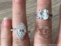 Close-up of two silver rings worn on fingers showing stone details and setting style.