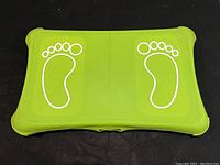 Top view of green Nintendo Wii Fit balance board with white footprint outlines.