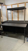 Two black folding tables, one stacked over the other showing full side views and foldable legs.