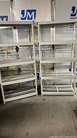Two beige Keter outdoor plastic shelving units side by side, each with five slatted shelves, against a wall with silver insulation panels.