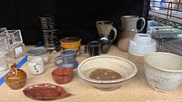 Full view of all pottery collection items showing various bowls, pitchers, mugs, and vases arranged on a table.