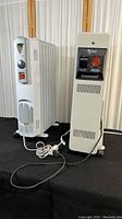 Two rolling space heaters side by side; De'Longhi oil-filled radiator style and Honeywell compact heater on wheels