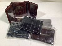 Photo of open dark brown tri-fold wallet showing card slots and currency section next to four black tri-fold wallets sealed in packaging.