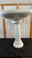 Full view of the pedestal supporting the sink bowl, showing glossy finish and classic column design.