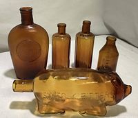 Overall view of five amber collectible bottles including pig-shaped bottle and four others