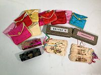 Overview of silk jewelry pouches, embroidered lipstick cases, wooden bookmarks, and fabric storage boxes.