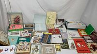 Wide view showing multiple vintage greeting cards, note paper sets, and memo pads including Hallmark and others. Cards have floral, seasonal, animal, and character illustrations.