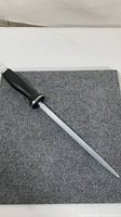 Full length view of the Zwilling J.A. Henckels sharpening steel with handle on grey fabric surface.