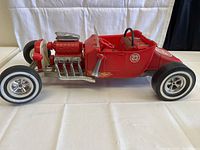 Full side view of red metal Big Red #23 Marx Super Hot Rod toy car showing metal frame, engine, wheels, steering wheel and detailed exhaust pipes.