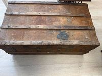Top view of the antique steamer trunk showing weathered wooden top with metal straps and a worn patch.