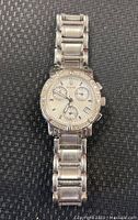 Front view of Bulova ladies watch with silver stainless steel band, crystal bezel, three subdials, and date window on face.