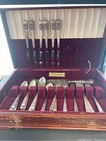 Full set of silver plated flatware in original box showing knives, forks, spoons in maroon holder with satin-lined lid.