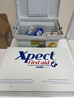 White metal first aid box branded Xpect First Aid by Cintas with OSHA compliance labeling and emergency contact info. Case measuring 18x12x6 inches.