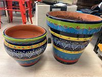 Photo of two terracotta pots side by side showing colorful hand painted design and glaze finish.