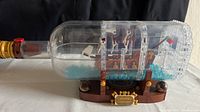 Full side view of the Lego assembled ship inside a clear plastic bottle set on its display stand.