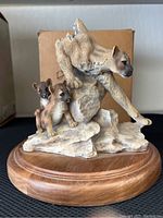 Full front view of mountain lion with two cub cubs on rocky base showing detailed fur texture and wooden platform.