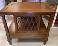 Front view of square wooden side table showing decorative lattice pattern on side and lower shelf