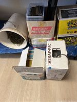 Photo of multiple boxes and a white bucket containing nails and fasteners including marked boxes Grip-Rite and Halstead labels