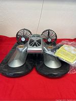 Front view of the silver remote control hovercraft with dual fans and accessory pack.