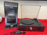 Texas Instruments Program Recorder model PHP 2700 in box next to Feir vinyl record player with wood grain finish and front control knob with attached cables.