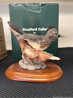 Front and side view of the roadrunner sculpture showing detailed feathers and base with original box in background.