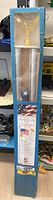 Full view of flag set in blue packaging with US flag and pole visible