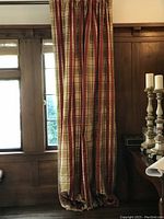 Full view of one silk plaid drapery panel hanging on rod, showing length and pattern.