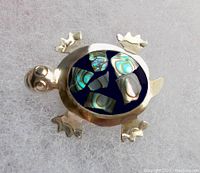 Front view of the turtle-shaped brooch showing the abalone shell inlay on its back and detailed silver body.