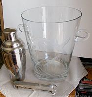 Full view of the crystal ice bucket with etched hummingbirds and cocktail shaker and ice tongs on cloth