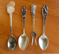 Four vintage sterling silver spoons and relish fork arranged on wooden surface, showing full items