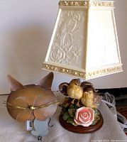 Vintage dresser lamp with embossed stiff-sided bird and rose shade and bird base, unlit.