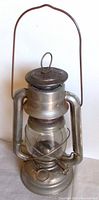Front view of vintage Dietz barn lantern showing metal construction and clear glass globe with wick adjustment knob.