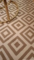 Close-up photo of beige and cream geometric square pattern on one of the polypropylene rugs showing texture and color contrast.
