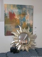 Abstract print on wall with sunburst mirror and ceramic elephant figurine in front