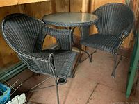 View of the bistro set showing the round table with top and two nesting chairs with plastic wicker and metal frames
