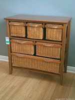 Front angled view of the wood cabinet showing six wicker baskets with handles arranged in three rows.