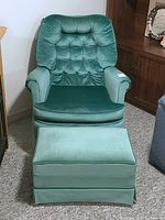 Front view of green velvet swivel rocker chair and matching ottoman on carpeted floor.