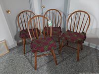 Four wooden hoop-back chairs, three with red and green tartan plaid cushions tied on seat, one chair without cushion