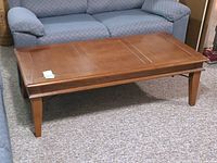 Wood coffee table placed in front of sofa showing top and side view.
