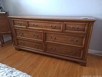 Front view of seven-drawer dresser showing three small top drawers and two rows of two larger drawers, brass-tone bail pull handles, medium oak finish