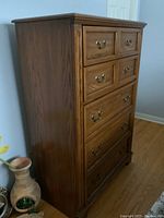 Front view showing five drawers with brass handles and wood finish.