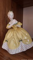 Front view of Royal Doulton The Last Waltz figurine showing woman in yellow dress holding an item.