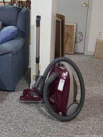 Full view of the Kenmore Elegance vacuum cleaner with hose and power head attachment standing on carpeted floor near furniture and wall art.