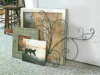All four wall art items arranged on floor: large framed birch tree print in beige frame, smaller framed acacia tree print in silver frame, gallery-wrapped boat print, and metal wire scroll sculpture