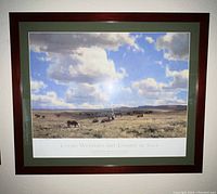 Framed poster showing a plains landscape with cattle under a cloudy sky, with wooden frame and green matting.